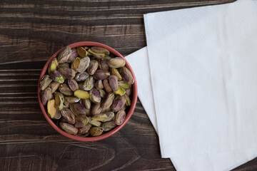 Pistachos pelados en un bol sobre una mesa de madera oscura.