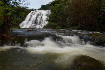 Owharoa Falls with water flowing downstream in the foreground, Karangahake Gorge, New Zealand.