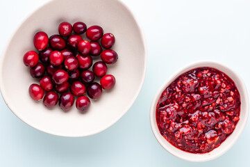 Cranberries in white bowl on pastel background.