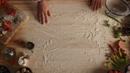 Chef hand preparing flour on wooden cutting board in food restaurant kitchen.