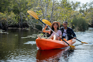 Asian attractive romantic young couple rowing kayak in a forest lake. 