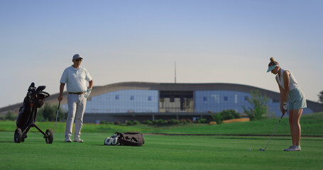 Business couple play golf on course. Two golfers practicing in country club.