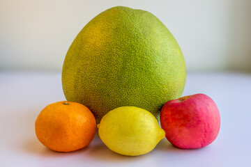 A pomelo, an orange and an apple, citrus fruit with an apple, isolated.