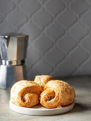 Croissants in white plate with coffee pot in back. Cozy good morning breakfast concept. Copy space