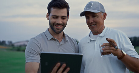Smiling golfers using tablet device talking family online at country club course