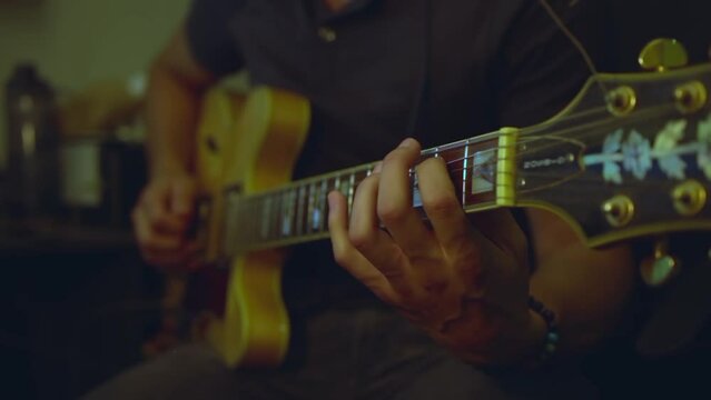 Closeup of a guy playing a semi hollow electric guitar.