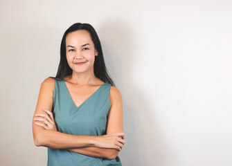 Obraz premium Asian woman with long back hair wearing green sleeveless blouse, smiiling and looking at camera on white background.