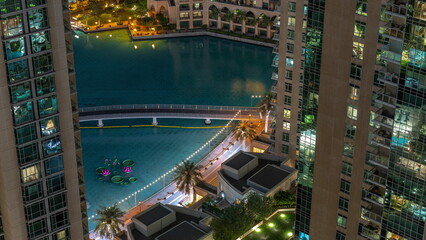 Fototapeta na wymiar Dubai fountains with walking area around aerial night view between skyscrapers timelapse.