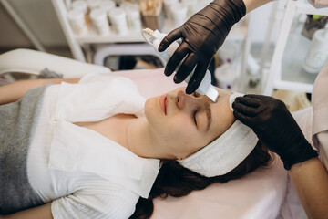 Cosmetologist's hand is making cavitation rejuvenation skin treatment. Facial treatment. Facial skincare. Beauty skin care. Rejuvenation treatment.