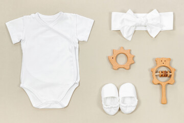 Mockup with a white wrap bodysuit on a soft beige background. Baby booties, headband, wooden...