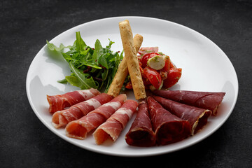 Meat appetizer with vegetable salad, arugula and grissini. Antipasti