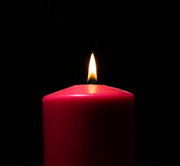 Burning red candle on black