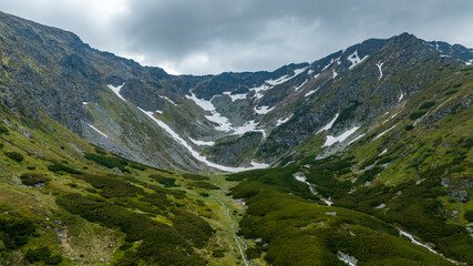Fototapeta na wymiar Rocky mountain peaks witw snow and greens aerial shot