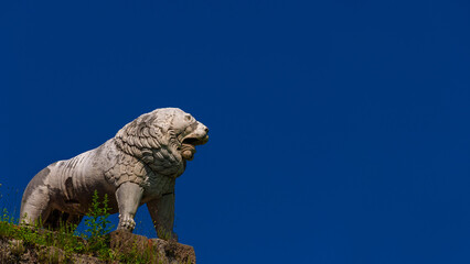 The Lion of Pisa, an ancient etruscan statue at the top of city ancient walls (with blue sky and...