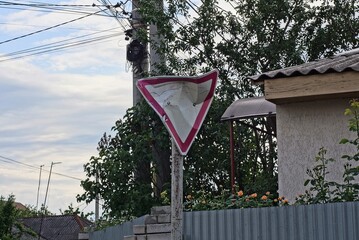 one dented metal triangular sign to give way on a post near the fence on the street
