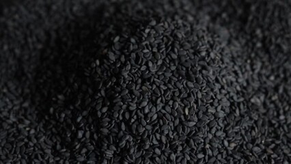 Pouring black sesame seeds in slow motion, close-up.