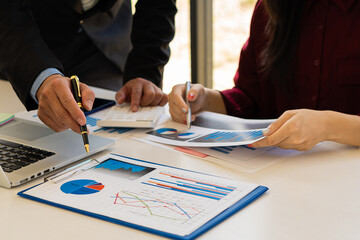 Two businessmen discuss graphing reports and analysis of financial budgets or cost companies. and use the calculator in the office Meeting with colleagues to brainstorm ideas on a business strategy.