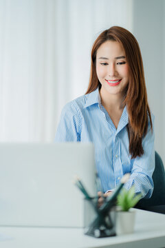 Asian businesswoman working on laptop computer in office with documents on desk woman looking at financial statistics data analysis chart profit growth business idea vertical image