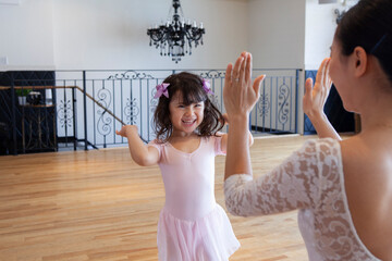 先生にハイタッチをするバレエダンサーの幼い少女