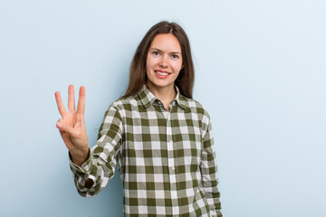 young adult pretty woman smiling and looking friendly, showing number three or third with hand...