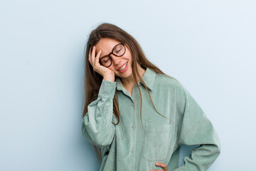 young adult pretty woman laughing and slapping forehead like saying d’oh! I forgot or that was a...