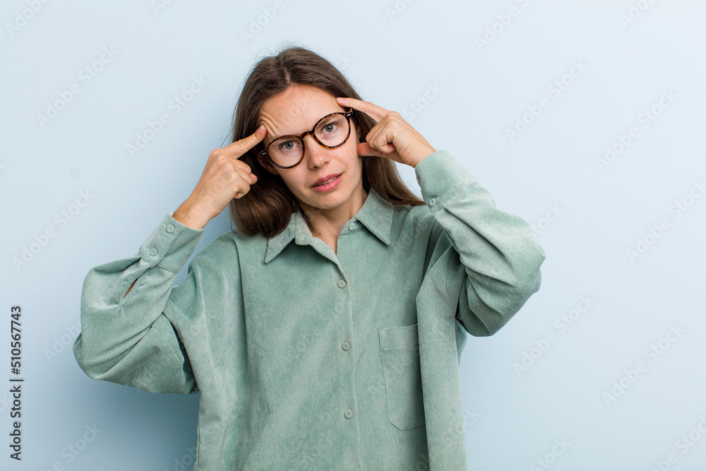 Wall mural young adult pretty woman with a serious and concentrated look, brainstorming and thinking about a challenging problem