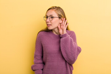 young adult blonde pretty woman looking serious and curious, listening, trying to hear a secret...