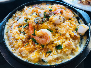 Sizzling seafood fried with eggs and batter served on hot plate in Thailand.