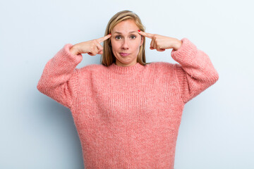 young adult blonde pretty woman with a serious and concentrated look, brainstorming and thinking...
