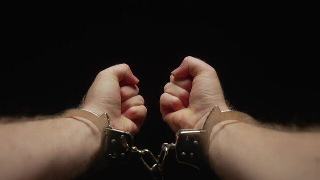 Man unsuccessfully attempting to break free from handcuffs
