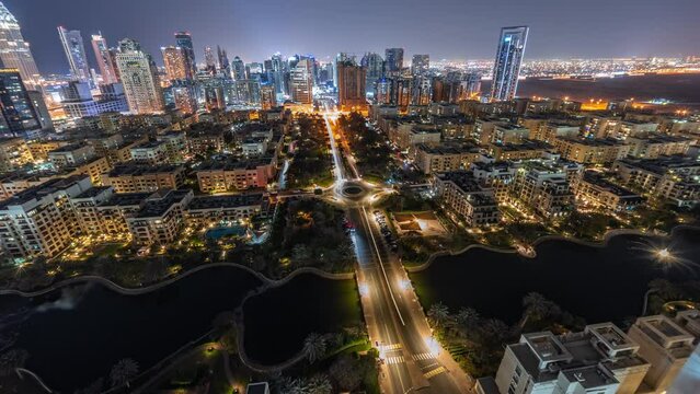 Panorama of skyscrapers in Barsha Heights district and low rise buildings in Greens district aerial night timelapse. Dubai skyline look down view