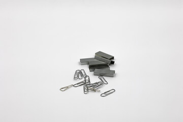 a lot of silver new staples for stapler and paperclips isolaon white background, set top view