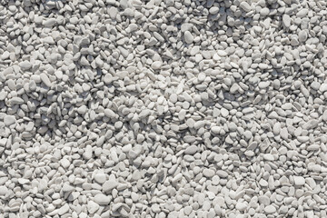 a lot of even identical white light rounded pebbles, sunny beach, top view, pattern background