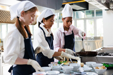Group of student girl learning. Cooking class. culinary classroom. group of happy young woman multi - ethnic students are focusing on cooking lessons in a cooking school. - obrazy, fototapety, plakaty