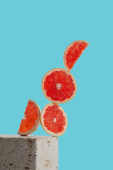 Creative concept with sliced levitating grapefruit on blue background