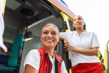 Two female nurses by the ambulance. Two paramedics by the ambulance, smiling.