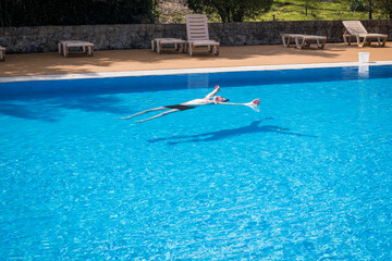An elderly gray-haired retired man swims in the pool. The concept of a healthy active lifestyle in old age