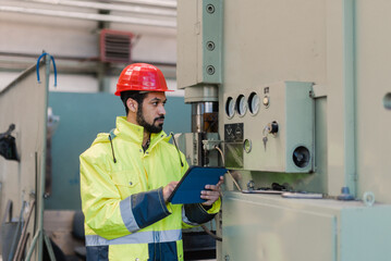 Portrait of engineer male using tablet while checking machines in industrial factory.