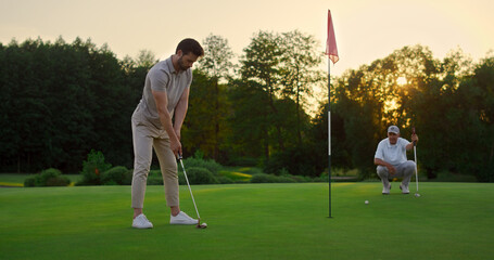 Sport men play golf game on field. Golfing team spend time on luxury resort.