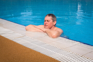 Senior adult swims in the pool. The concept of a healthy active lifestyle in old age