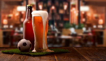 Buttle and glass of beer, soccer ball on green grass