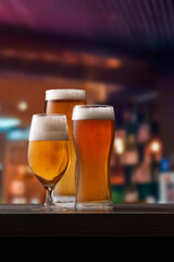 Three different glasses of beer on counter in pub.