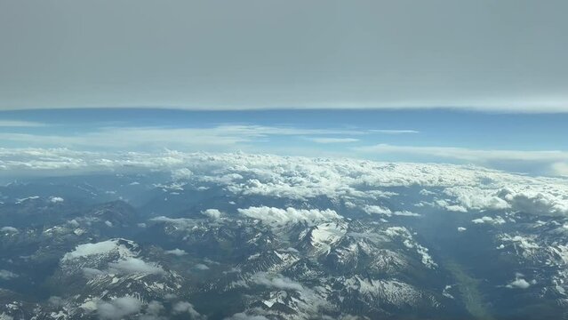 Aerial side view from a jet cockpit. Pilot pov, from the italian Alps mountains during cruise level while flying bellow a flat layer of stratus. 4K