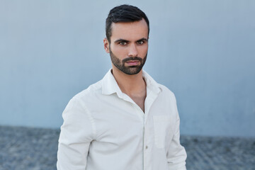 Serious bearded ethnic guy looking at camera on street