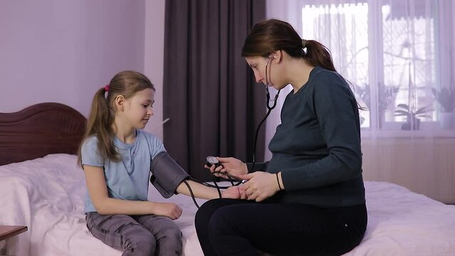 the mother controls her childs blood pressure. mother and daughter in the bedroom, mandatory medical checkup early in the morning