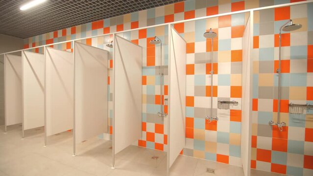 Empty public shower room with separated cabins and colorful tiles pattern on walls at contemporary sports center