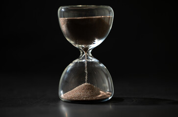 hourglass (sand clock) on a black background, Hourglass as time passing concept for business deadline, Life-time passing concept, with copy space