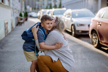 Mother hugs her young son on the way to school, and a mother and boy say goodbye before school.