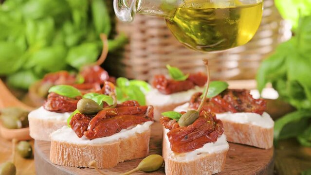 bruschetta with dried tomatoes, fresh soft cheese, basil, dried herbs, capers and spices. Traditional Italian, Spanish or Greek appetizer snack. video. 4k. For social networks and advertising