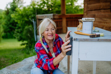 Senior woman cleaning and renovating garden furniture and getting the garden ready for summer